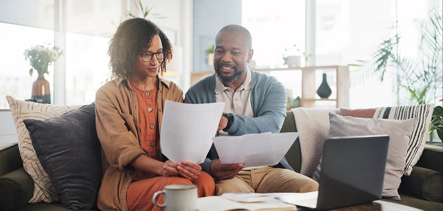 Couple reviewing financial documents at home, highlighting Polymath’s personalized financial guidance.