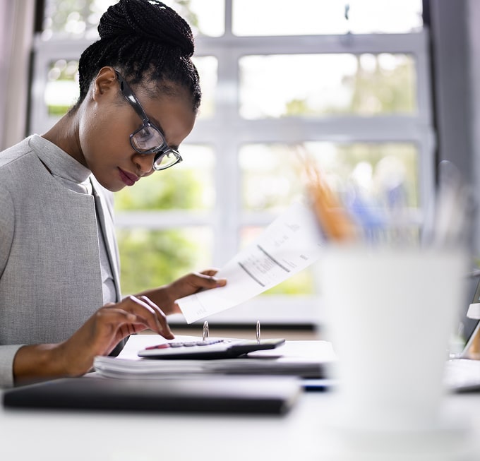 Professional woman calculating figures and reviewing a financial report, highlighting accuracy in financial analysis.