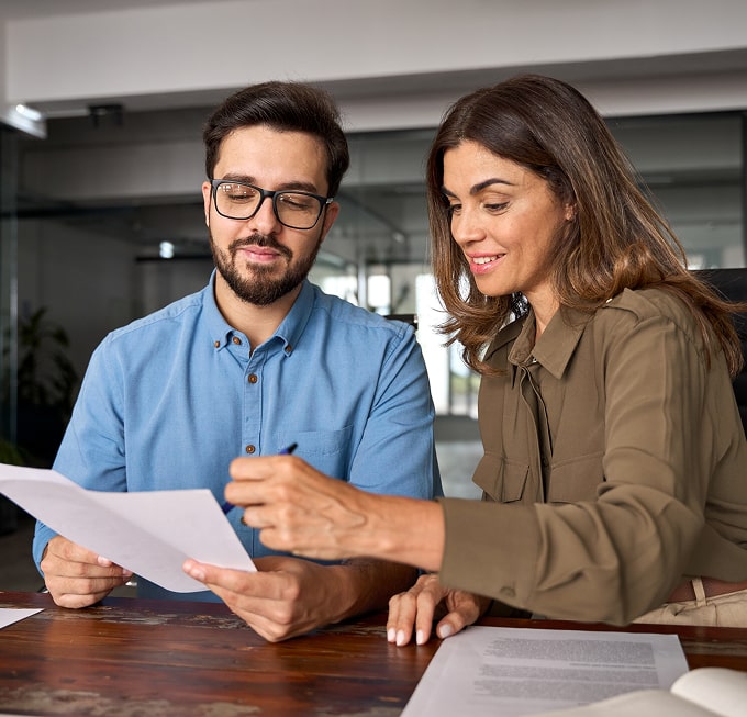 Two professionals reviewing financial documents at a table, highlighting the personalized, collaborative approach of Polymath Investments.